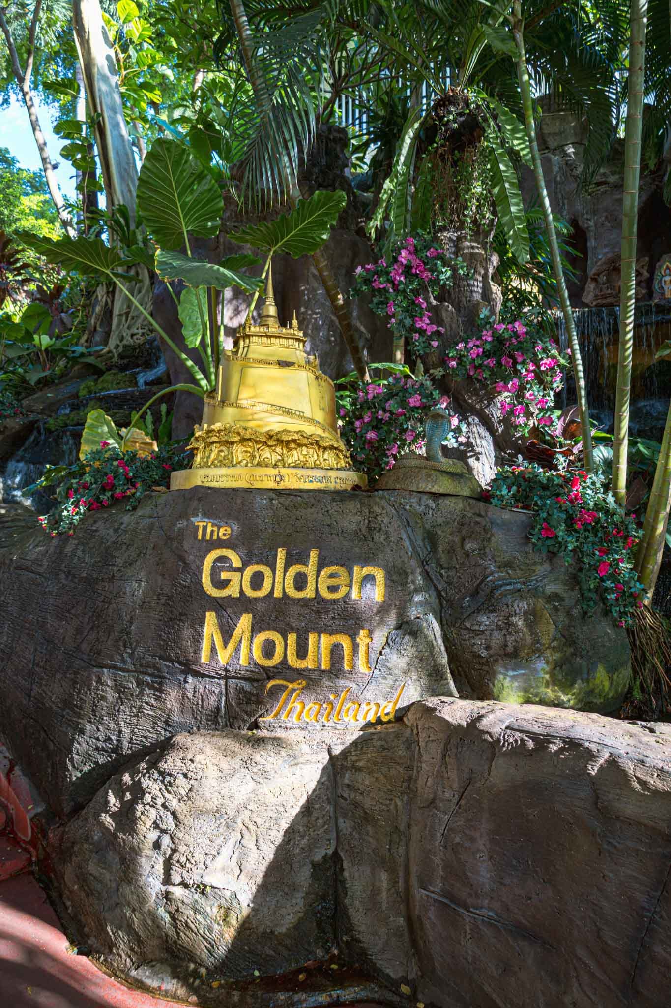The Golden Mount in Bangkok, Thailand - Yati Travel A large rock with a sign reading "The Golden Mount," located at the Golden Mount in Bangkok, Thailand. Must-Visit Temples in Bangkok.