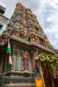 Colorful Sri Maha Mariamman Temple in Bangkok, featuring a large ornate tower against a clear blue sky. Must-Visit Temples in Bangkok.