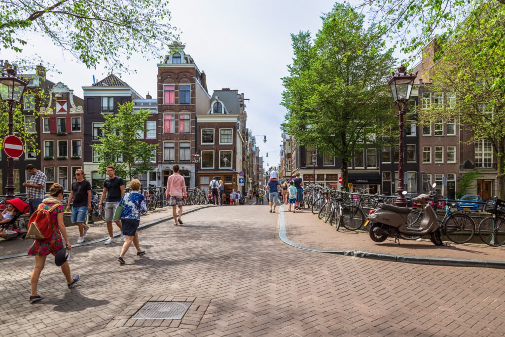 Residents and tourists walk across the bridge over the Herengracht to the Oude Spiegelstraat in the center of the capital Amsterdam. best things to do in amsterdam