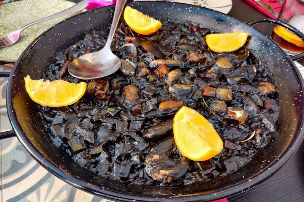 Black Paella featuring mushrooms served in a pan on a table at El Gastronauta, Málaga, Spain. Best Places to Eat in Málaga.