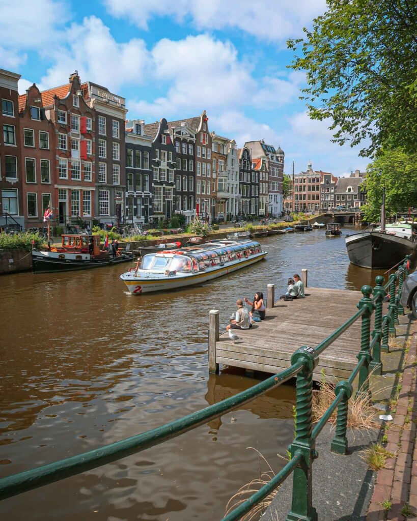 Boats and classic Dutch houses in the scenic canals of Amsterdam, The Netherlands. Amsterdam Travel Guide.