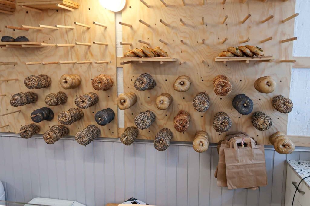 A vibrant wall at Breadwinner in Amsterdam featuring an array of bagels hanging for display, highlighting their diversity. Best Bakeries in Amsterdam.