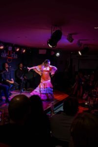 A woman in a vibrant flamenco dress performs passionately on stage at Alegría Flamenco y Gastronomía in Málaga, Spain. Best Things to Do in Málaga.