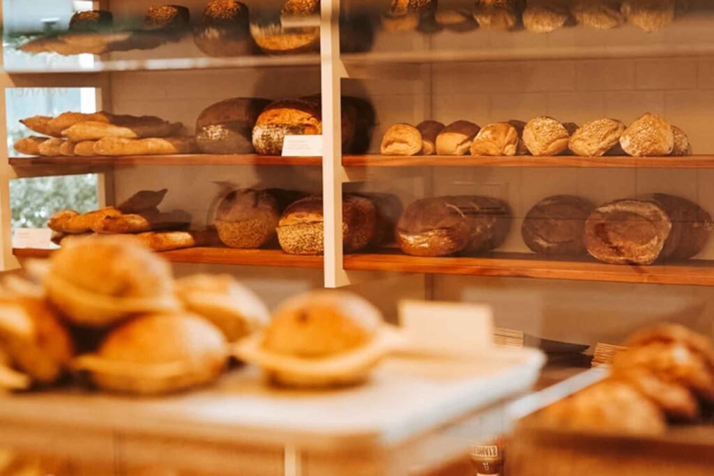 Fresh breads and sourdoughs displayed on shelves at Louf Bakery in Amsterdam, inviting and warm atmosphere. Best Bakeries in Amsterdam.