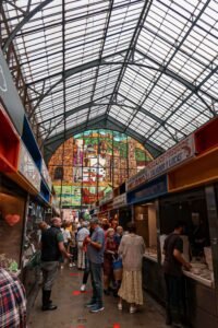 A bustling market scene inside Mercado de Atarazanas in Málaga, Spain, with a large crowd of shoppers and vendors. Best Things to Do in Málaga.
