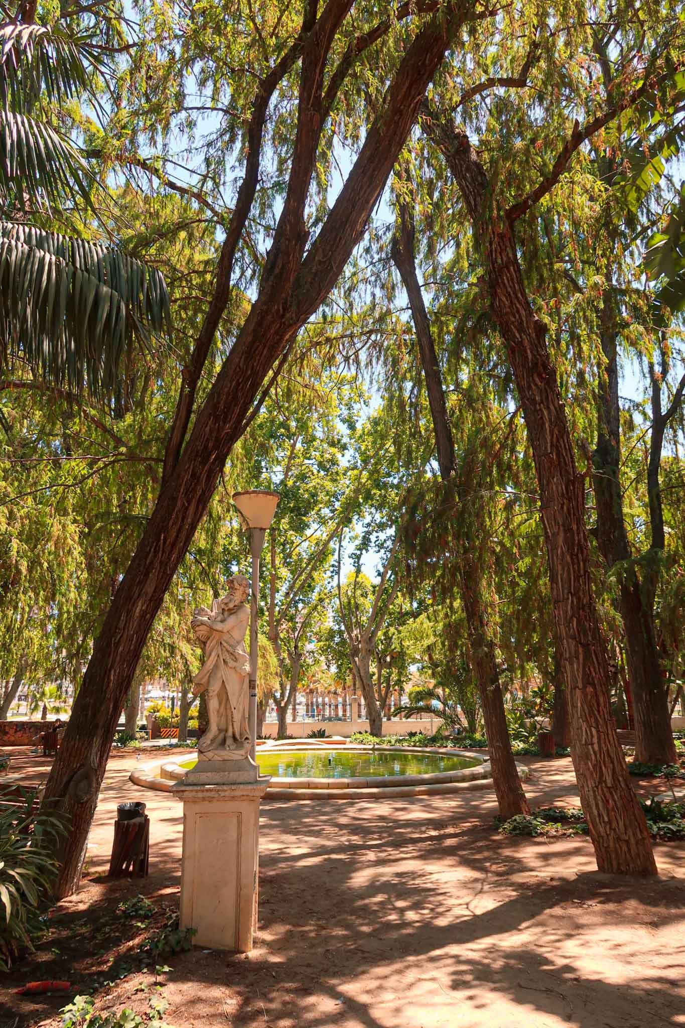 Inside Parque de Málaga V2 - Yati Travel A statue in Parque de Málaga, surrounded by greenery and park scenery. Best Things to Do in Málaga.