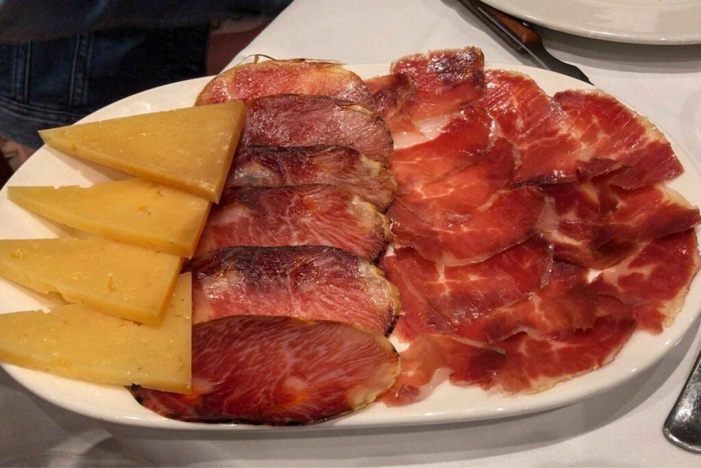 A meat and cheese platter served at Mesón Ibérico in Málaga, Spain, showcasing a variety of cured meats and cheeses. Best Places to Eat in Málaga.