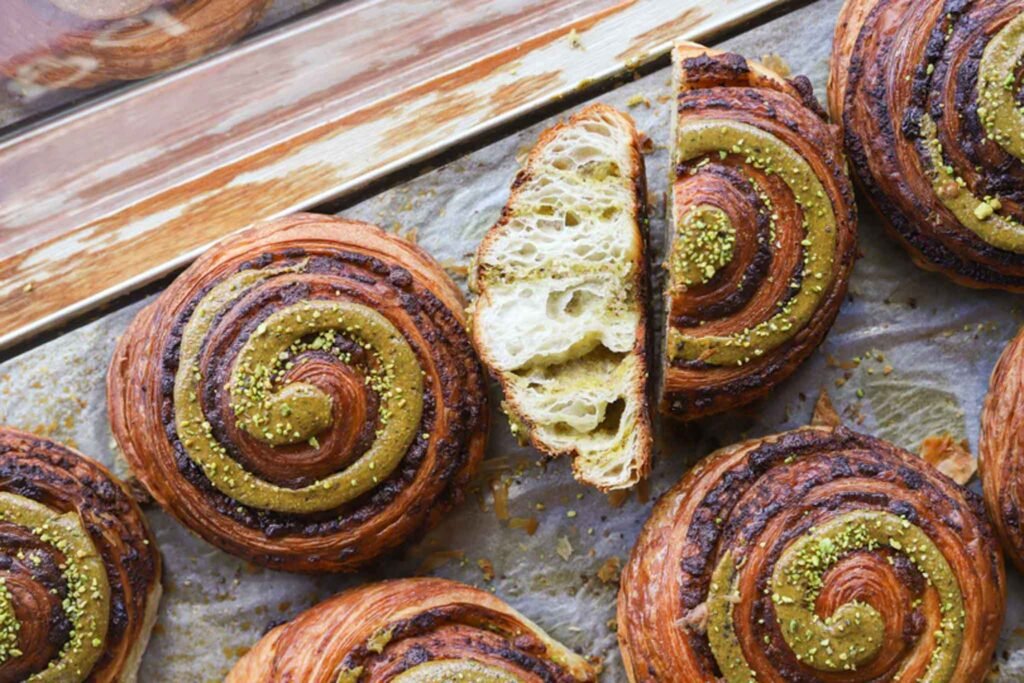 A tray of Pistachio Escargot Pastries with vibrant green swirls, displayed at Grammes in Amsterdam. Best Bakeries in Amsterdam.