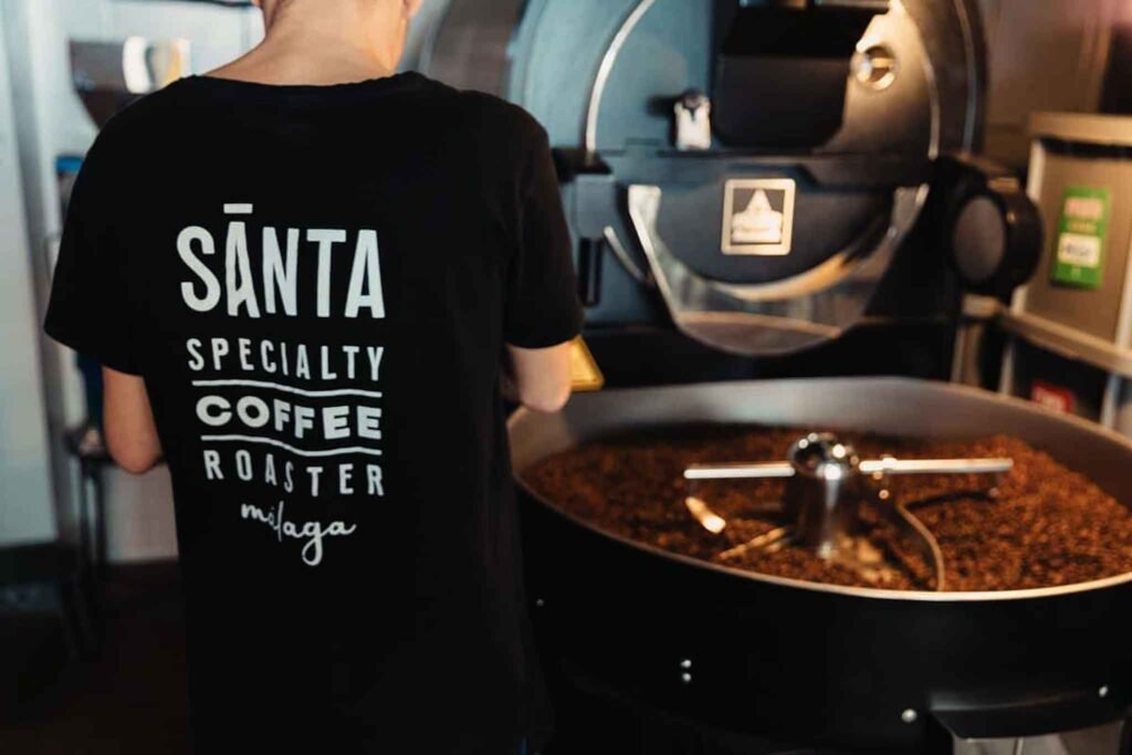 A man in a Santa shirt stands by a coffee machine at Santa Soho Specialty Coffee in Málaga, Spain. Best Places to Eat in Málaga.