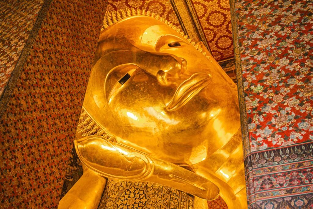 The Reclining Buddha in Bangkok, Thailand V2 - Yati Travel The Reclining Buddha statue in Bangkok, Thailand, gleams in gold, representing tranquility and spiritual significance in Wat Pho. Bangkok Travel Guide. Must-Visit Temples in Bangkok.
