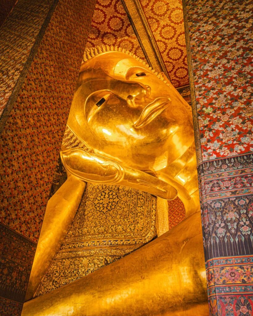 The Reclining Buddha in Bangkok, Thailand - Yati Travel A majestic golden statue of the Reclining Buddha in Bangkok, Thailand, symbolizing peace and enlightenment. Bangkok Travel Guide.