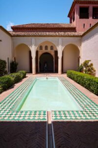 The pool at the Alcazaba in Málaga, Spain, features green and white water, set against a backdrop of ancient walls. Best Things to Do in Málaga.