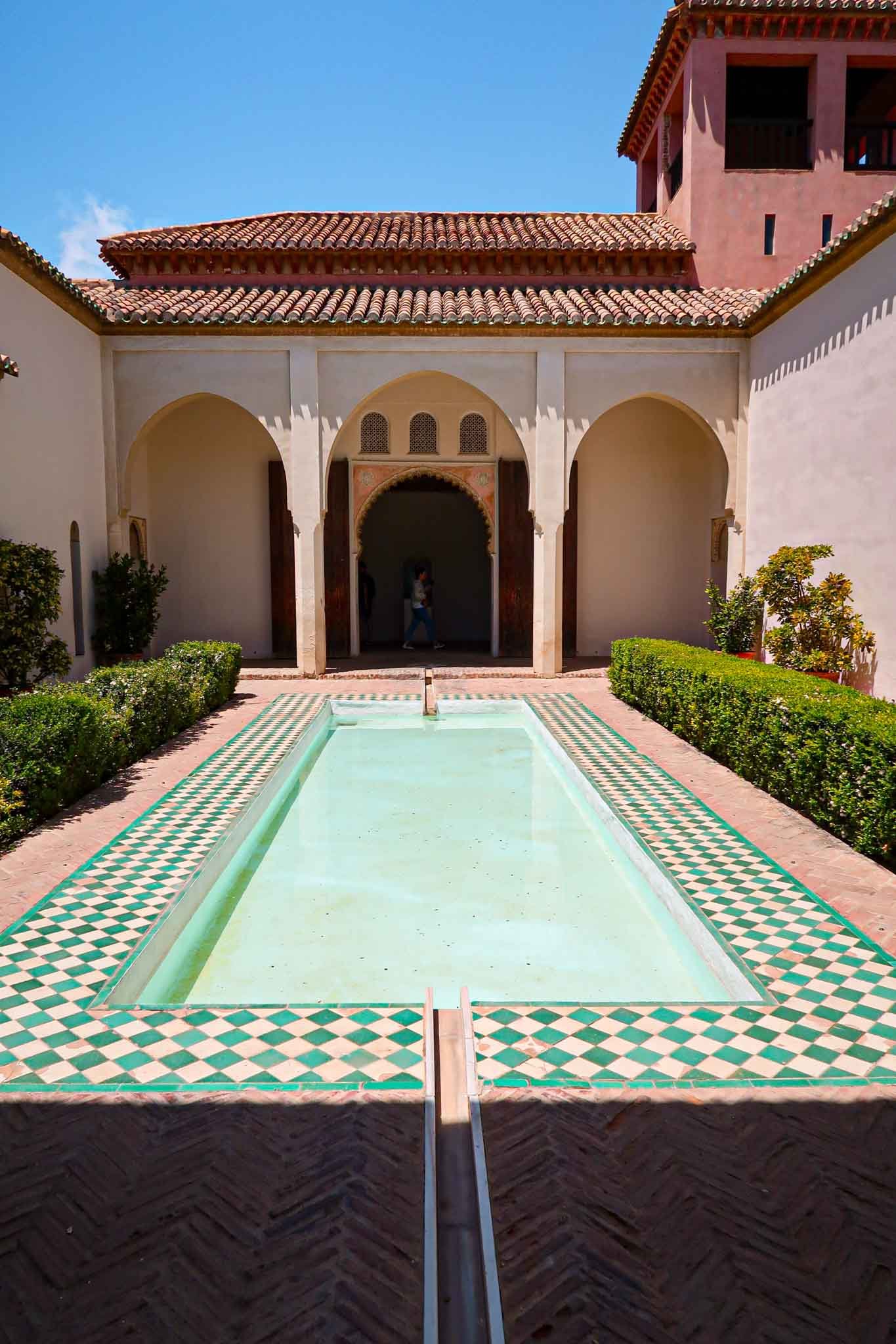 Water bath inside Alcazaba in Málaga, Spain - Yati Travel The pool at the Alcazaba in Málaga, Spain, features green and white water, set against a backdrop of ancient walls. Best Things to Do in Málaga.